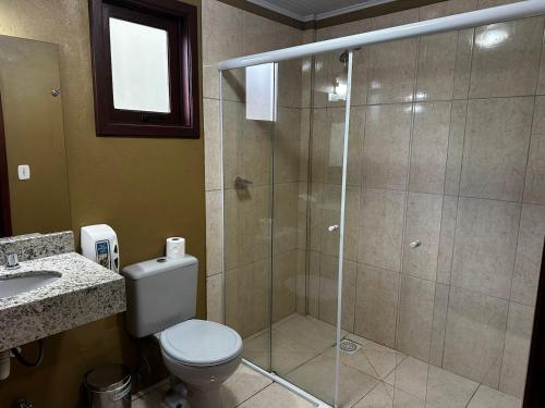 a bathroom with a shower with a toilet and a sink at Pousada Canela Garden in Canela