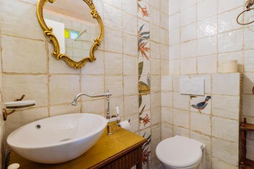 a bathroom with a sink and a toilet and a mirror at Casa Colorida in Vila do Bispo