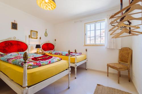 two beds in a room with a table and a chair at Casa Colorida in Vila do Bispo