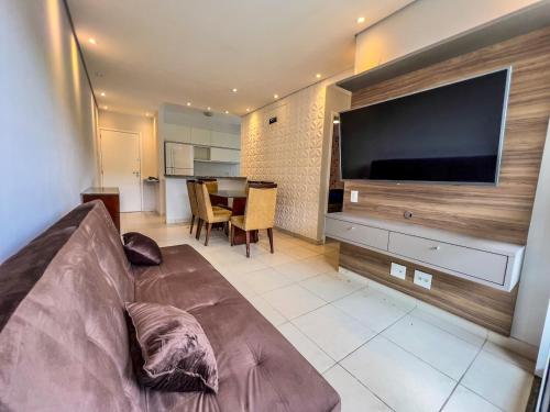 a living room with a couch and a large flat screen tv at R7 Conforto total com piscina in Guarujá