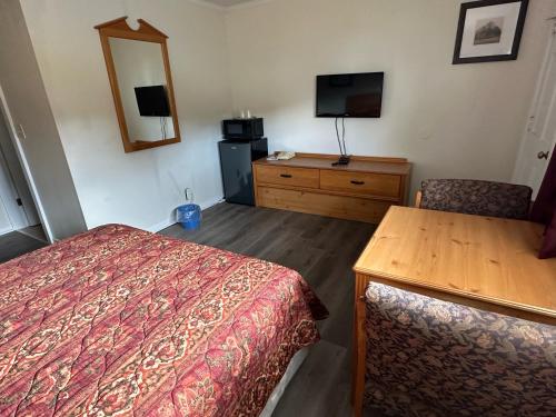 a hotel room with a bed and a table and a mirror at Oakdell Motel WATERFORD CT in Waterford