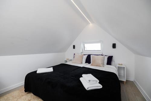 a bedroom with a black bed with towels on it at Nowoczesny przytulny apartament in Banino