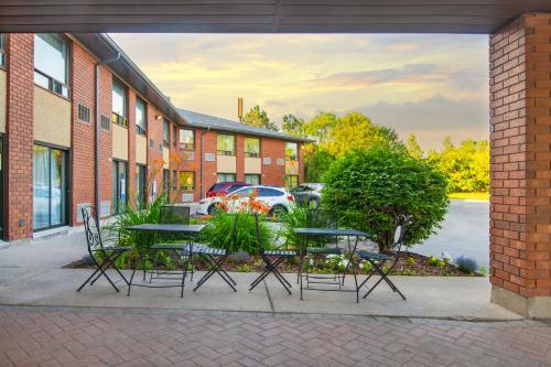 a patio with tables and chairs in front of a building at Comfort Inn Hwy 401 in Kingston