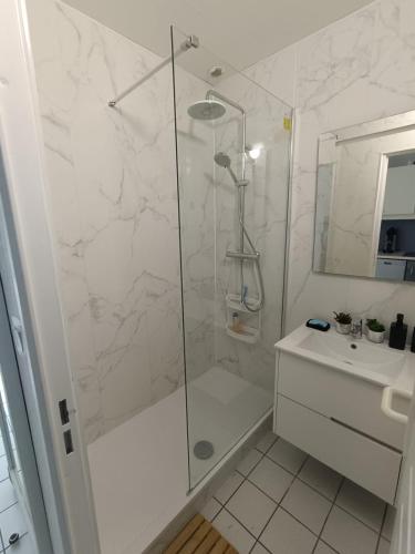 une salle de bain blanche avec une douche et un lavabo dans l'établissement cottage golf de saint laurent, à Ploemel