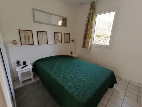 une chambre avec un lit vert et une fenêtre dans l'établissement cottage golf de saint laurent, à Ploemel