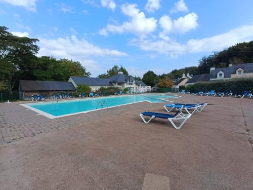 une piscine avec deux chaises longues à côté dans l'établissement cottage golf de saint laurent, à Ploemel