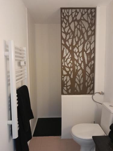 a bathroom with a toilet and a tree mural on the wall at Le Lodge Merlin Studio 2 personnes in Barraux