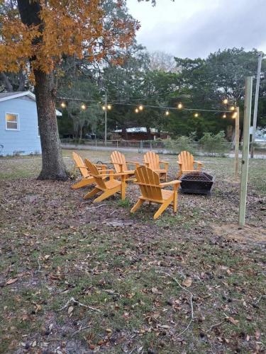 a row of wooden chairs sitting next to a tree at Retro by the Bay Close to Beach Eglin PetFriendly in Freeport