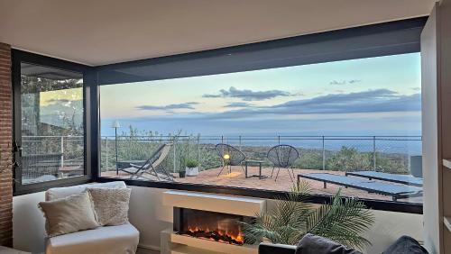a living room with a fireplace and a large window at Rahal Luxury- Between Etna & Sea in Catania