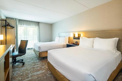 a hotel room with two beds and a desk at Comfort Inn Hwy 401 in Kingston