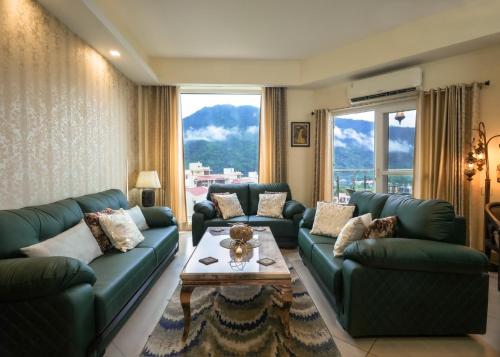a living room with green couches and a table at Aarohan by Ganga kripa in Narendranagar