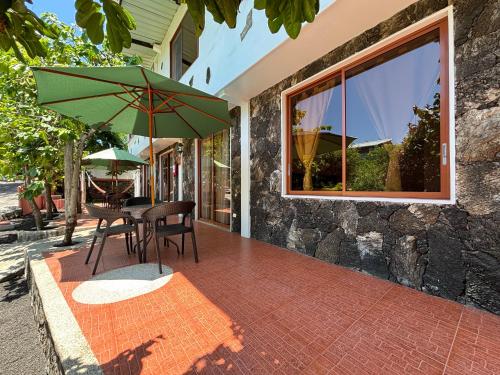 a patio with a table and a green umbrella at Lava House Hostal in Puerto Ayora