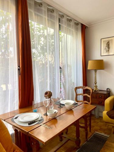 une table en bois avec des assiettes et des bols devant une fenêtre dans l'établissement Appartement avec terrasse, à Paris