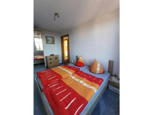 a bed with red and orange pillows in a room at Holiday apartment mountain idyll in Hänischmühle