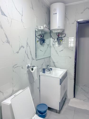 a white bathroom with a toilet and a sink at J&B Apparts Wifi in Mvolyé