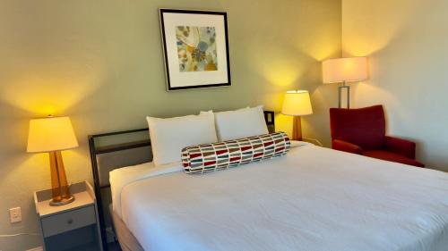 a hotel room with a bed and a red chair at Marina Village Inn in Alameda