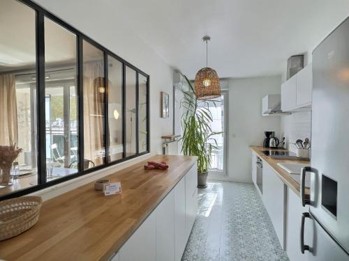 une cuisine avec des armoires blanches et un comptoir en bois dans l'établissement Le tête dOr, BNBConciergerie, à Villeurbanne