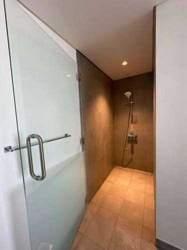 a bathroom with a shower with a glass door at Ajmal Chalet in Al Ḩamrīyah