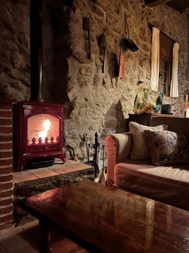 a living room with a fireplace and a couch at Casa Rural Los Cuartos de Gredos in Los Cuartos