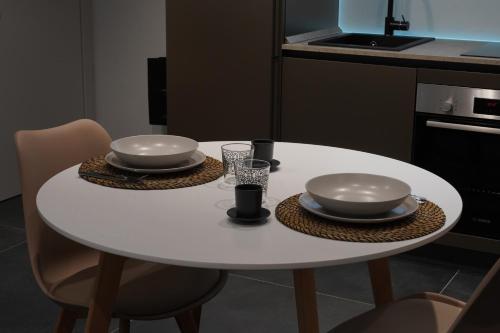 a white table with two plates and bowls on it at BLUMI Apartment in Molfetta