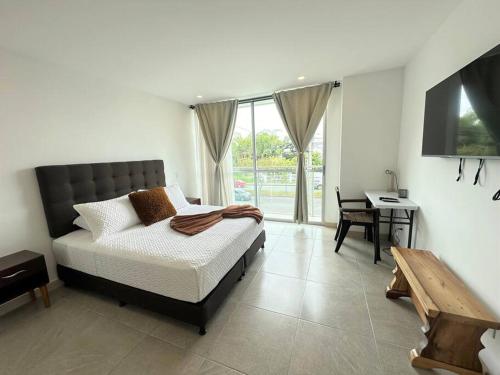 a bedroom with a bed and a table and a desk at Belmonte218-Apartaestudio en Av centenario con piscina gym bbq in Armenia