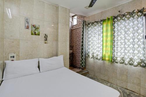 a bedroom with a white bed and a window at Hotel O DREAMZZ INN in Nagpur