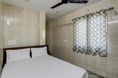 a bedroom with a white bed and a window at Hotel O DREAMZZ INN in Nagpur