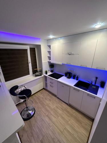 kuchnia z białymi szafkami i krzesłem w pokoju w obiekcie Studio apartment w mieście Valmiera