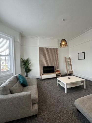 a living room with a couch and a coffee table at Spacious Victorian Birkdale Apartment with Garden in Southport