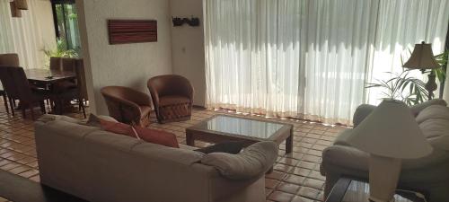 a living room with a couch and chairs and a table at Cancun Villa Agave, access to the Beach! in Cancún