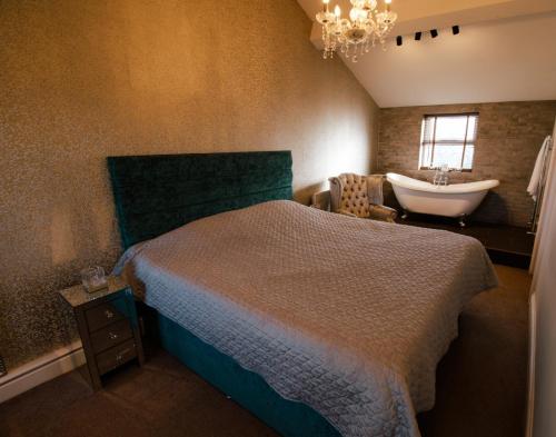 a bedroom with a bed and a sink and a tub at The George Wright Boutique Hotel, Bar & Restaurant in Rotherham