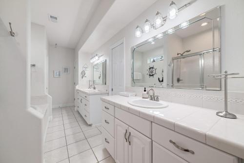 ein weißes Badezimmer mit zwei Waschbecken und einem Spiegel in der Unterkunft The Yellow House at Herons Walk in Pensacola