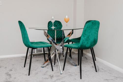 a glass table with green chairs in a room at Samuel place in Corby