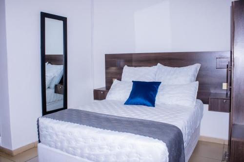 a bedroom with a large white bed with a blue pillow at Mongi Guest House in Harare
