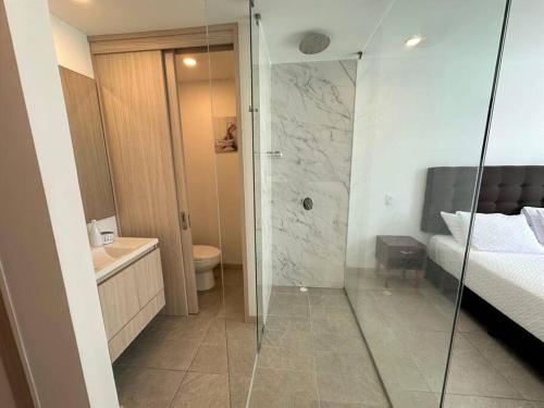 a bathroom with a shower and a toilet and a bed at Belmonte205-Apartaestudio en Avenida con piscina, terraza,bbq in Armenia
