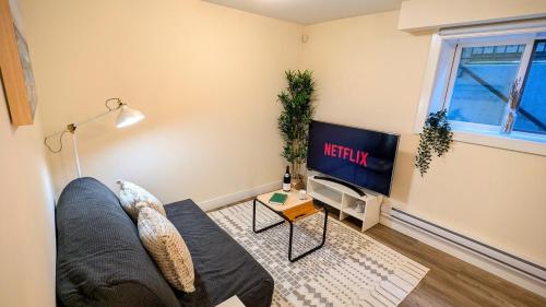 a living room with a couch and a tv at New 1 bedroom suite North Vancouver in Lynn Creek