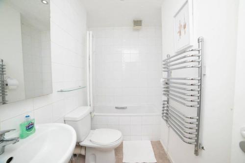 a white bathroom with a toilet and a sink at Wilson House - Camden in London