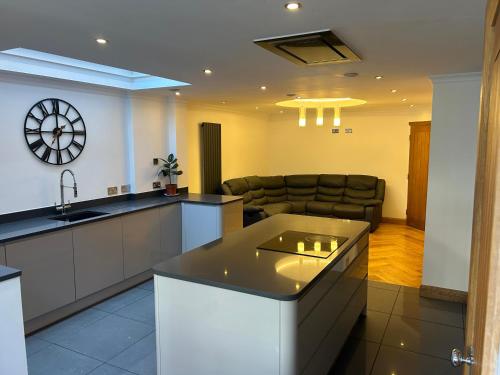 a kitchen and living room with a couch and a clock at Entire Seaside Home 6 Private BedRooms Sleeps 10,4 Minute Walk To Station in New Brighton