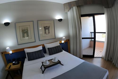 a bedroom with a large white bed and a balcony at Bonaparte Hotel - Excelente Apartamento #1019 in Brasilia