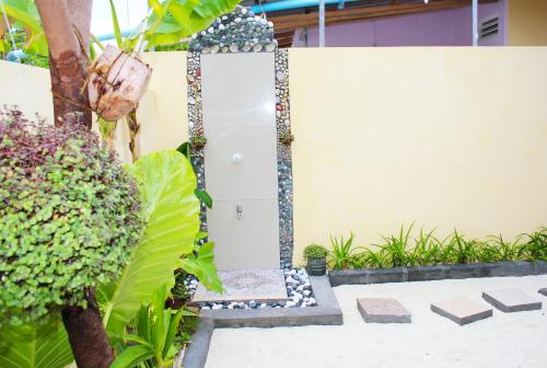 a garden with a white fence and plants at Kaafu Inn Guraidhoo in Guraidhoo