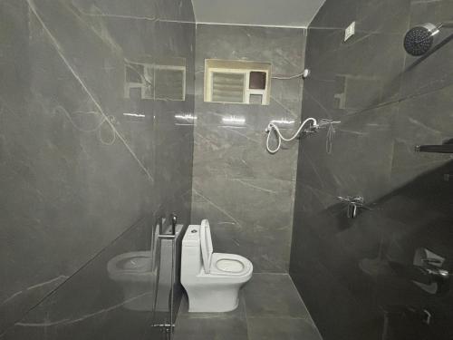 a bathroom with a white toilet and a shower at Nest Inn Homestay in Tirupati