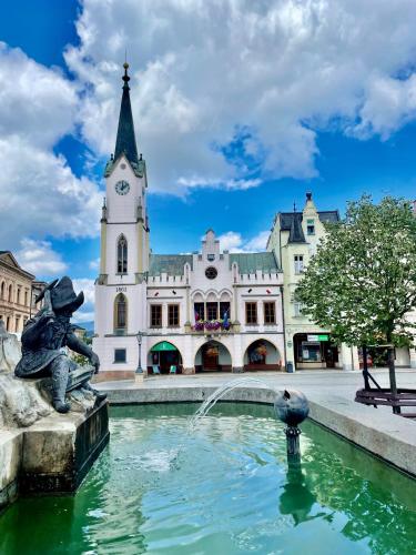 a fountain in front of a building with a clock tower at Apartment NAVI- Modern studio in Krkonoše foothills in Staré Buky