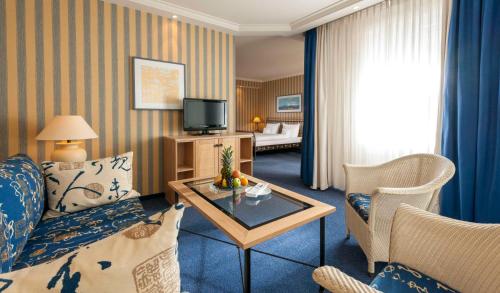 a living room with a couch and a table in a room at Dorint Strandhotel Binz/Rügen in Binz