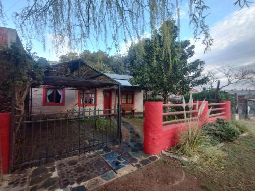 a house with a red fence in front of it at De viento y luna in General Pico