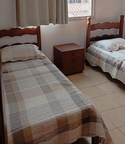 a bedroom with two beds and a table and a window at AP Ventidor in Guarapari
