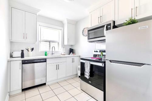 a white kitchen with white cabinets and a refrigerator at Central Corktown Apartment for City Explorers in Hamilton