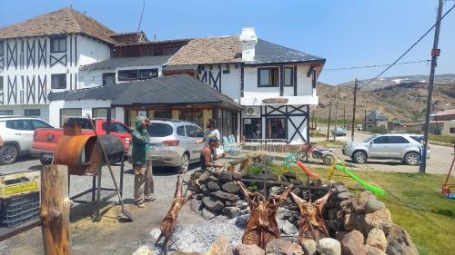 a group of people standing around a fire pit in front of a house at Hualcupen Complejo in Copahue