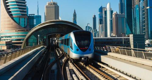 a blue and white train on the tracks in a city at Pathfinder Partition Room in Barsha Heights Tecom in Dubai
