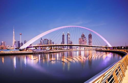 a bridge over a river with a city in the background at Pathfinder Partition Room in Barsha Heights Tecom in Dubai