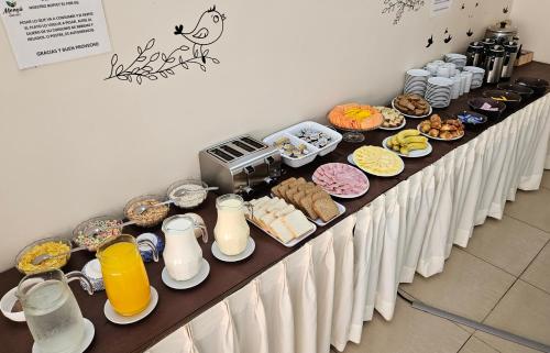 una mesa larga con comida para el desayuno y bebidas. en Mensú Grand Hotel, en Puerto Iguazú